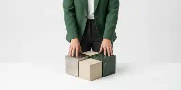 Unlocking Value: A Comparative Analysis of Finance, Benefits, and Education Strategies A person in a green blazer touching three geometric blocks representing finance, benefits, and education strategies on a minimalist background, symbolizing integrated growth.